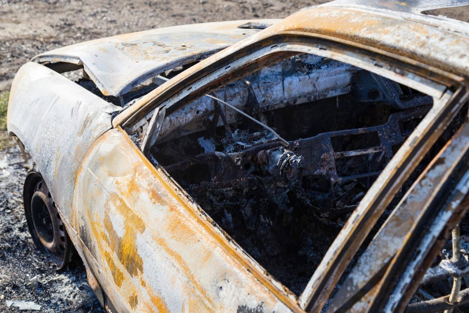 Severely rusted car body with orange corrosion streaks from coastal exposure in the UAE