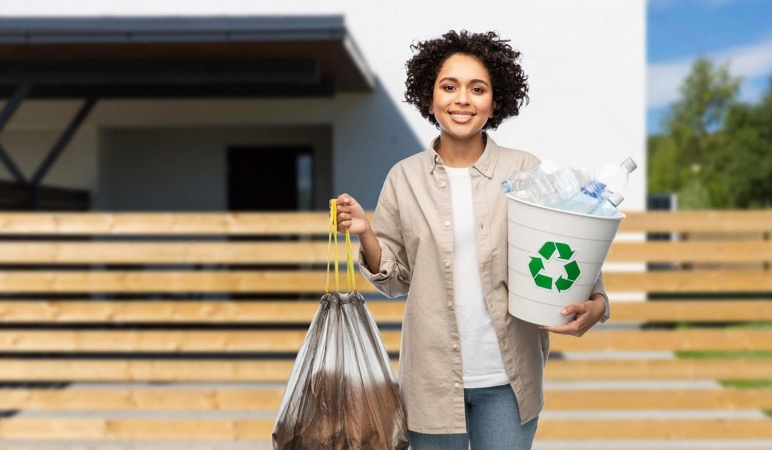 Smiling woman holding a recycling bin and waste bag in front of a Dubai villa